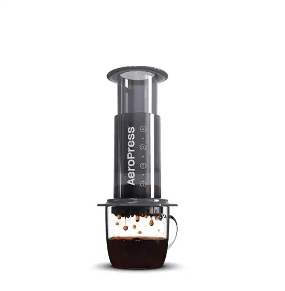Aeropress coffee maker with a glass of coffee on a white background