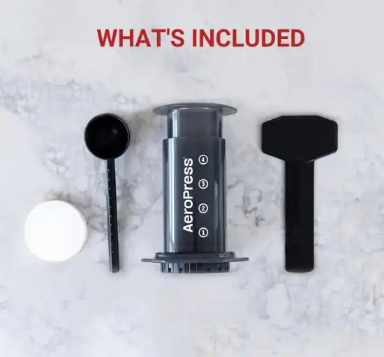AeroPress coffee maker with components on a marble surface, text 'WHAT'S INCLUDED' at the top.