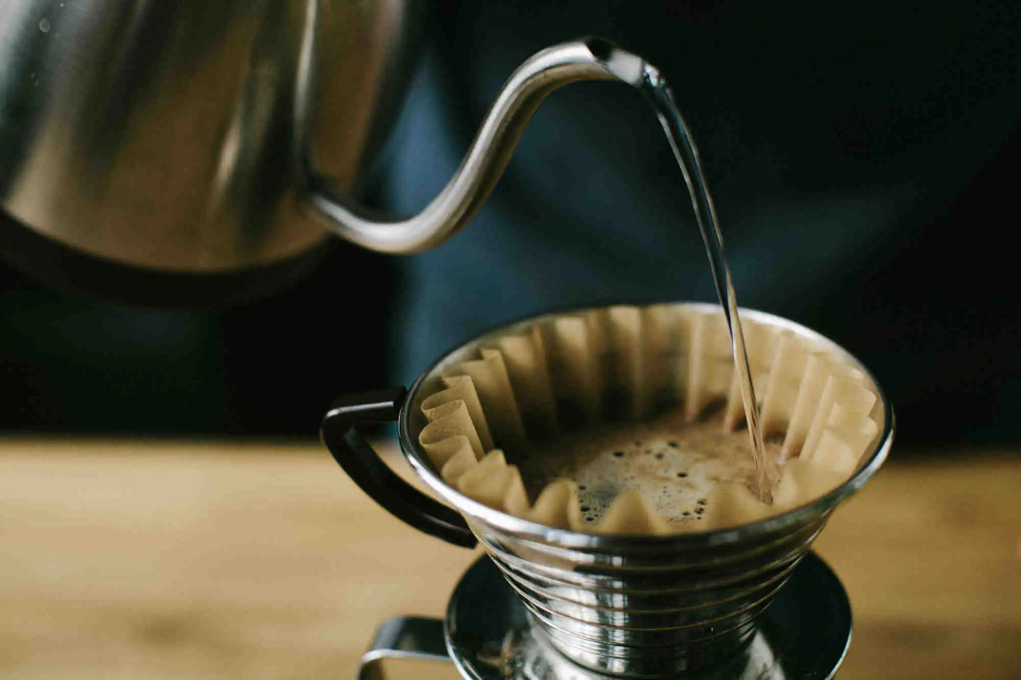Coffee being poured into a filter basket on a wooden surface