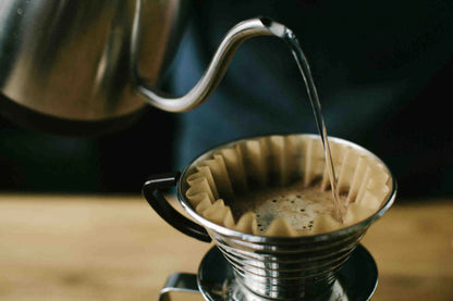 Coffee being poured into a filter basket on a wooden surface