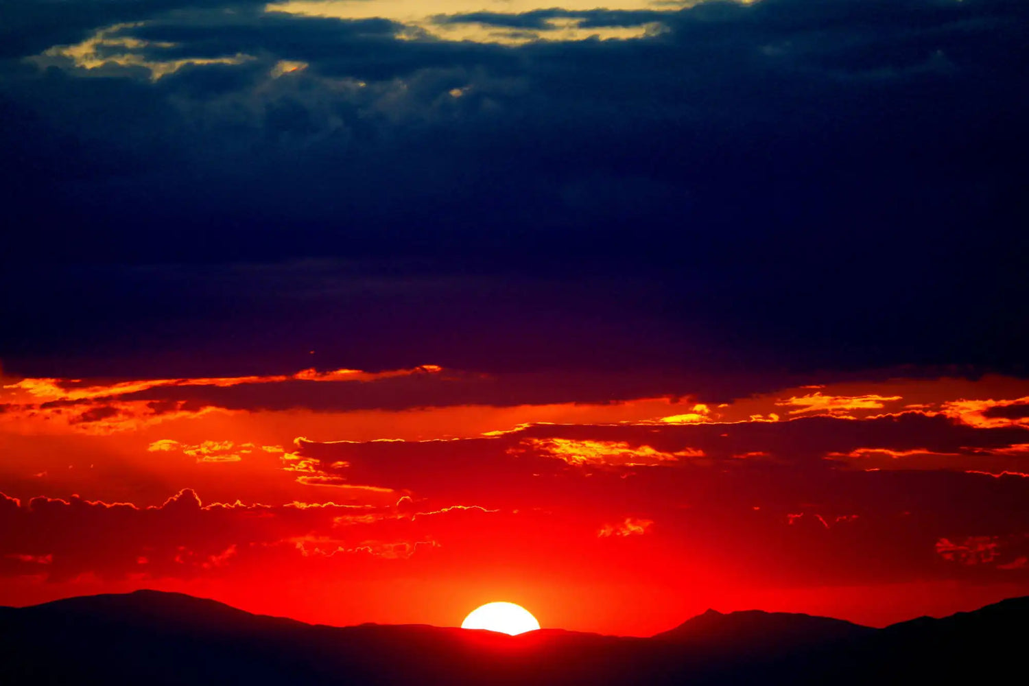 Sunset over a mountain range with vibrant orange and red colors.