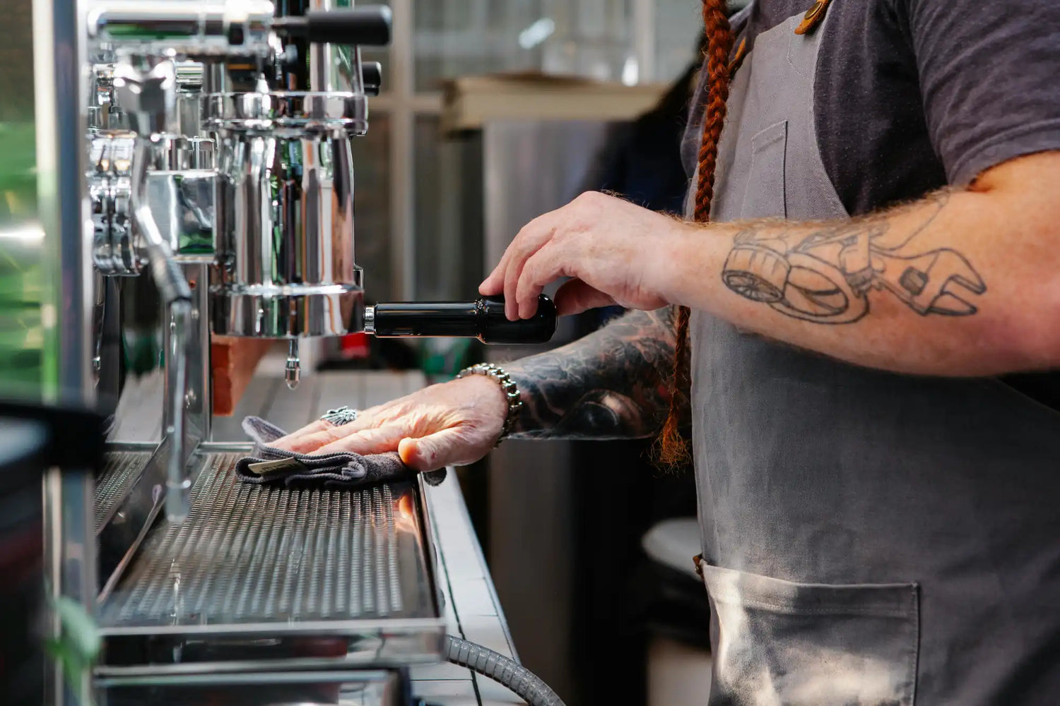 Barista preparing coffee using an espresso machine in a professional setting.